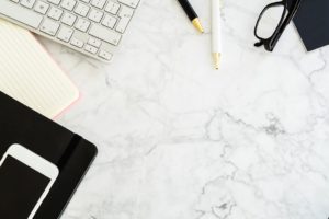 marble table, laptop keyboard, glasses, mobile phone and a notebook 