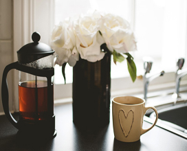 Heart coffee cup next to a white flowers vase